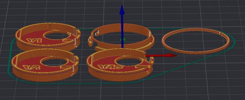 Puede incluir: Una representaci&oacute;n 3D de varios objetos circulares de color naranja y rojo con un agujero central. Los objetos tienen un dise&ntilde;o detallado, con las letras "V43" visibles en algunos. Tambi&eacute;n hay un anillo naranja separado, junto con un contorno verde.