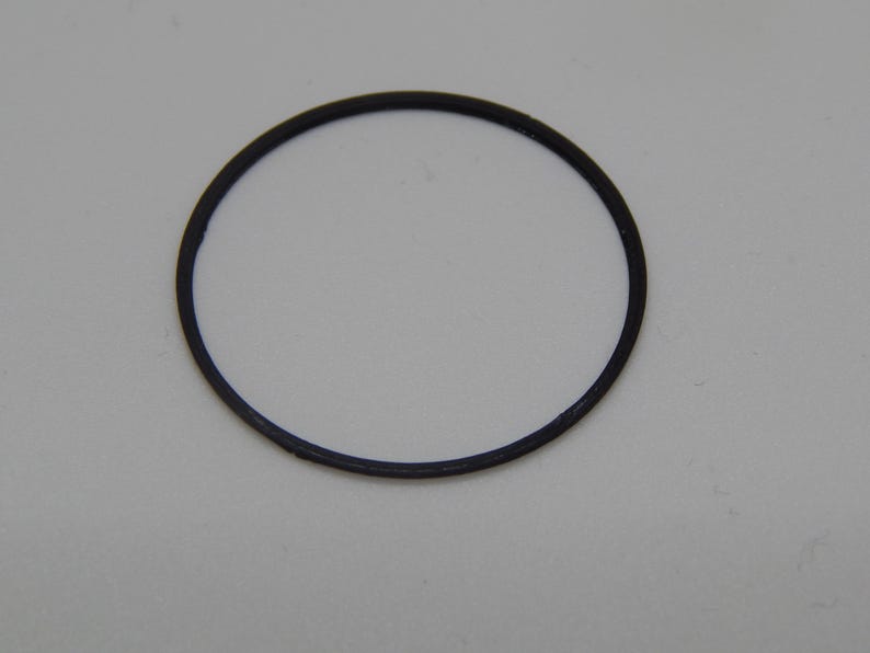 Puede incluir: Una junta t&oacute;rica de goma negra, de forma circular, aislada sobre un fondo blanco. La junta t&oacute;rica es un bucle cerrado, probablemente utilizado para sellar. El di&aacute;metro es de aproximadamente 2,5 cm.