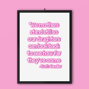 May include: A framed print with a pink quote that reads "We mothers stand still so our daughters can look back to see how far they've come - Ruth Handler".