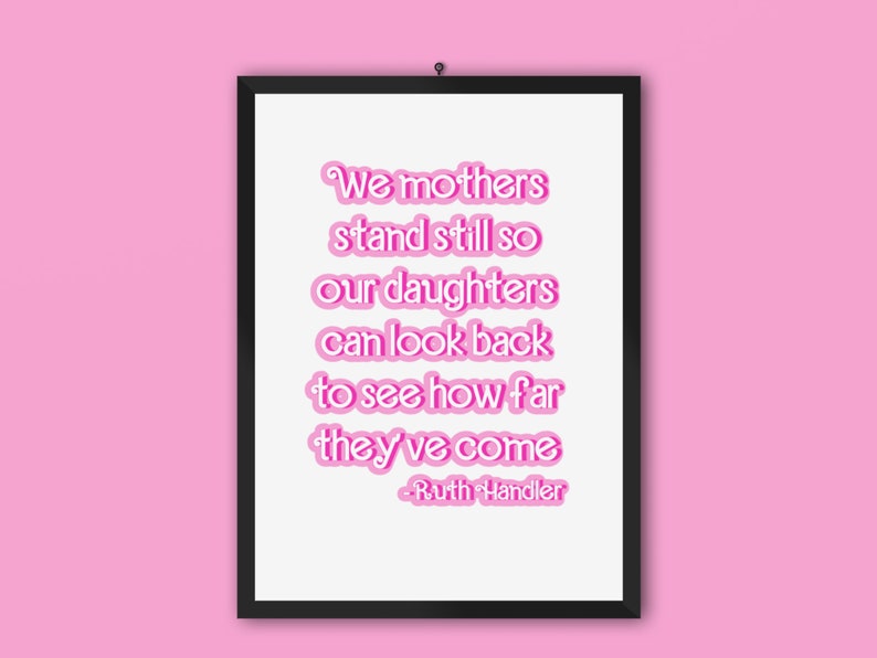 K&ouml;nnte beinhalten: Ein gerahmter Druck mit einem rosafarbenen Zitat, das lautet: "We mothers stand still so our daughters can look back to see how far they've come - Ruth Handler".