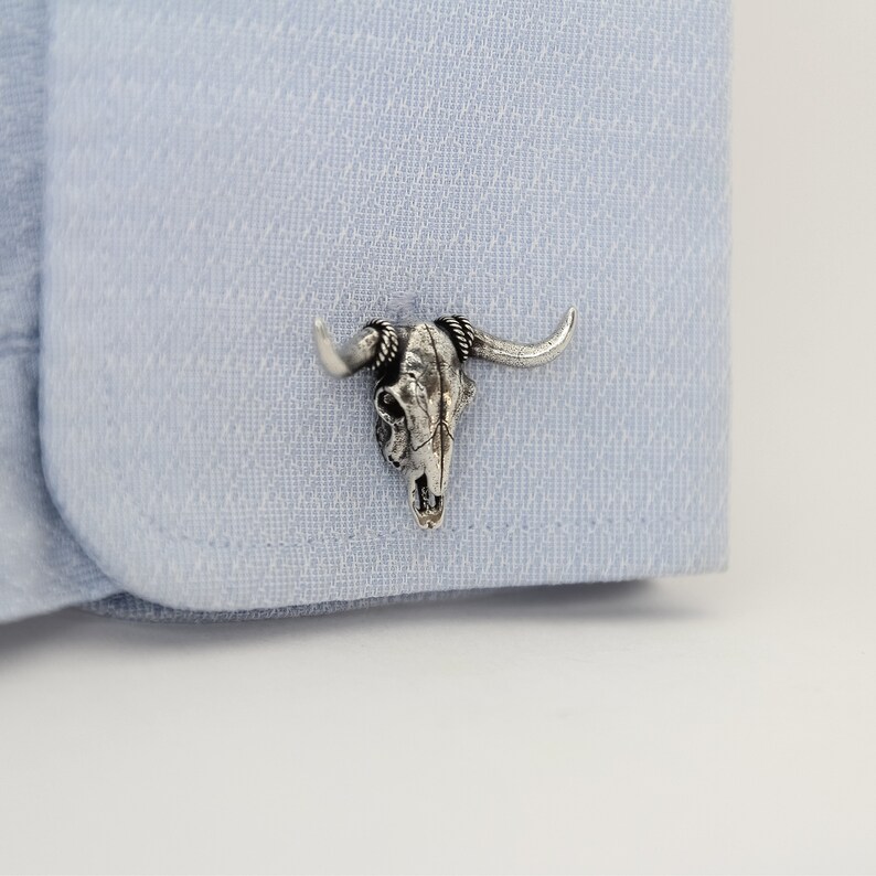 Puede incluir: Gemelos de plata con un dise&ntilde;o detallado de cr&aacute;neo de toro.