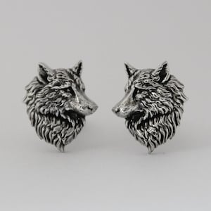 May include: A pair of silver wolf head cufflinks. The wolf heads are detailed and realistic.
