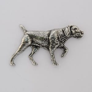 Könnte beinhalten: Eine silberfarbene Metallfigur eines Hundes in Laufpose. Der Hund hat eine detaillierte Fellstruktur und ist wahrscheinlich eine Jagdhunderasse. Die Figur befindet sich auf einem schlichten weißen Hintergrund.