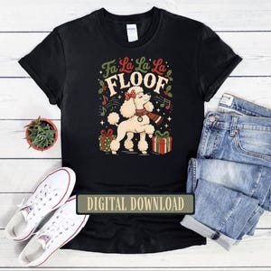 May include: A black t-shirt featuring a graphic of a white poodle wearing a red polka dot bow and a striped scarf. The text reads Fa La La La FLOOF, surrounded by musical notes, holly leaves, and two gift boxes with red and green bows.