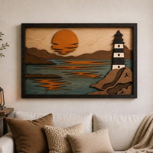 May include: Wooden wall art featuring a sunset over the ocean with a lighthouse. The artwork has a black frame and is made of layered wood in shades of orange, brown, blue, and white. The lighthouse is black and white.