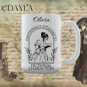 Peut inclure: Une tasse en céramique blanche avec une illustration en noir et blanc d'une femme lisant un livre. Le texte "Emotionally Attached to Fictional Characters" est imprimé sur la tasse. Le nom "Olivia" est imprimé en haut de la tasse.