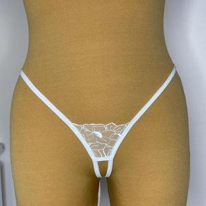 Può includere: Lingerie in pizzo bianco con un motivo floreale. La lingerie ha spalline sottili e una schiena scoperta.