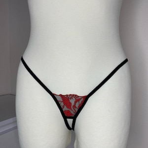 May include: Black and red lace lingerie with a delicate floral pattern. The lingerie has a thin black strap design.