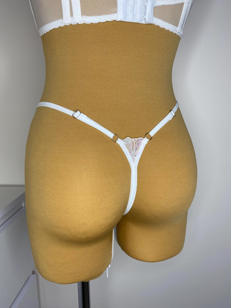 Puede incluir: Lingerie de encaje blanco con tirantes delicados y un dise&ntilde;o floral. La lencer&iacute;a se muestra en un maniqu&iacute;.