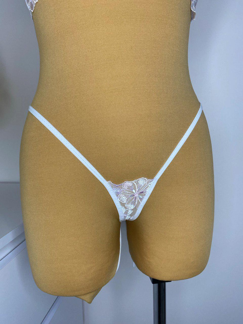 Puede incluir: Lingerie de encaje blanco con un dise&ntilde;o floral. La lencer&iacute;a tiene tirantes finos y una tela delicada y transparente.