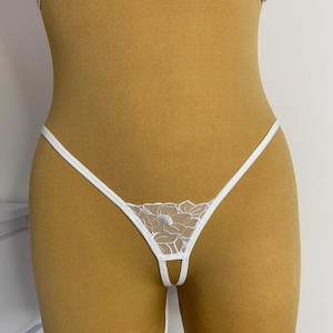 May include: White lace lingerie with a floral design. The lingerie has a high-cut leg and a low-rise waist.