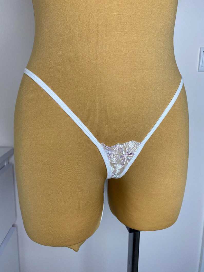 Puede incluir: Lingerie de encaje blanco con un dise&ntilde;o floral. La lencer&iacute;a est&aacute; en un maniqu&iacute;.