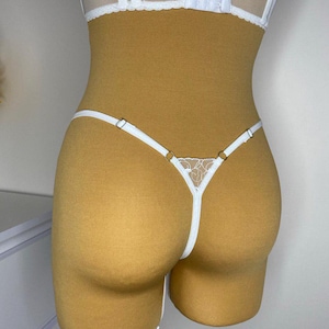 May include: White lace lingerie with delicate straps and a floral design. The lingerie is made of a soft, sheer fabric and has a comfortable fit.