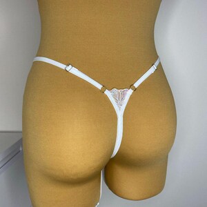 Puede incluir: Lingerie de encaje blanco con tirantes ajustables y un delicado dise&ntilde;o floral.