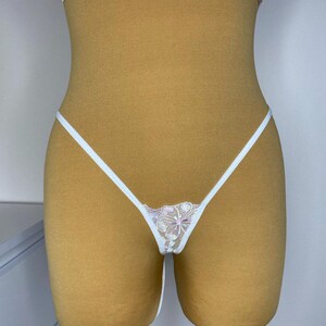 Puede incluir: Lingerie de encaje blanco con un dise&ntilde;o floral. La lencer&iacute;a est&aacute; en un maniqu&iacute;.