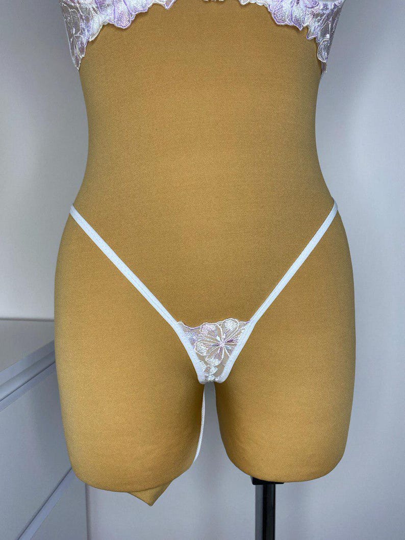Puede incluir: Lingerie de encaje blanco con un dise&ntilde;o floral. La lencer&iacute;a est&aacute; en un maniqu&iacute;.