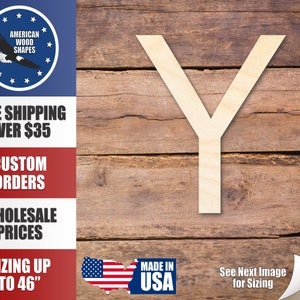 May include: A wooden letter Y, cut from a light brown piece of wood, is displayed on a woodgrain background. The letter is approximately 12 inches tall. The background is a close-up of a wooden plank.