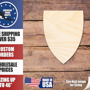 May include: A plain, light brown wooden shield shape. The shield is on a woodgrain background. The text "MADE IN USA" is in the lower right corner of the image.