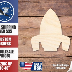 May include: A wooden rocket ship cutout, unfinished and ready to be painted or stained. The cutout is on a woodgrain background.  The image also includes text that says "Made in USA" and "See Next Image for Sizing".