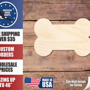 May include: A plain, unfinished wooden dog bone shape. The bone is made of natural wood and is ready to be painted or stained. The bone is shown on a wood background.