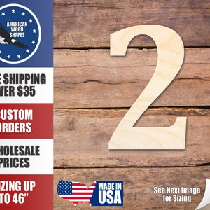 May include: A wooden number two cutout, painted white, against a woodgrain background. The number is large and appears to be made of plywood. The image also includes text that says "Made in USA" and "See Next Image for Sizing".