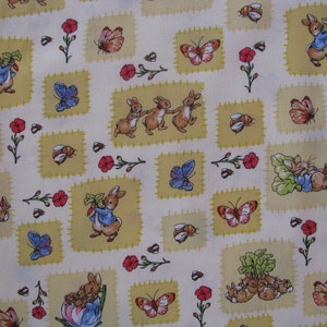 May include: A cream-colored fabric featuring a repeating pattern of Peter Rabbit characters in blue jackets, orange butterflies, red flowers, and small bees. The rabbits are depicted in various poses, including holding vegetables and dancing, set against light yellow squares.