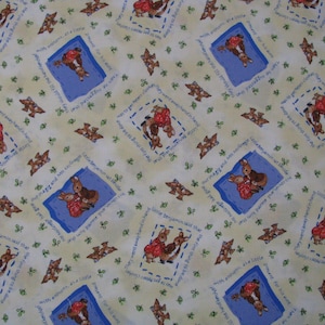 May include: A light yellow fabric featuring a repeating pattern of Peter Rabbit illustrations inside blue rectangular frames. The design includes small green clover motifs and printed text snippets from the story surrounding each character scene.