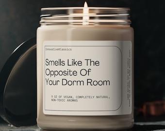 May include: A beige candle in a glass jar with a white label that reads "Smells Like The Opposite Of Your Dorm Room". The label also says "9 oz of vegan, completely natural, non-toxic aromas".