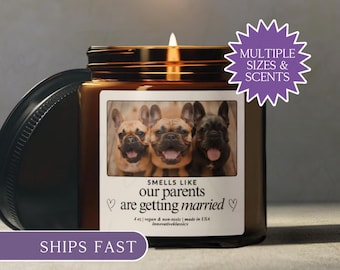 May include: A lit candle in a brown glass jar with a black lid. The label features three French bulldogs and the text "Smells like our parents are getting married." A purple starburst graphic says "Multiple Sizes & Scents."