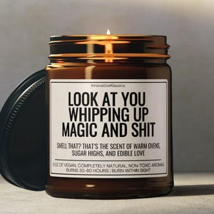 K&ouml;nnte beinhalten: Eine brennende braune Glas-Kerze mit schwarzem Deckel. Auf dem Etikett steht "LOOK AT YOU WHIPPING UP MAGIC AND SHIT". Der Text darunter lautet "SMELL THAT? THAT'S THE SCENT OF WARM OVENS, SUGAR HIGHS, AND EDIBLE LOVE".