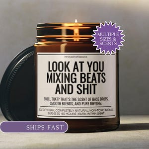 May include: A brown glass jar candle with a black lid, featuring a label that reads "LOOK AT YOU MIXING BEATS AND SHIT." The label also states the candle's scent and burn time. A purple starburst graphic indicates multiple sizes and scents.