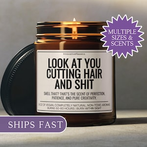 Puede incluir: Una vela en tarro de cristal marr&oacute;n con tapa negra. La vela tiene una etiqueta blanca con el texto "LOOK AT YOU CUTTING HAIR AND SHIT". La vela est&aacute; etiquetada como "InnovativeKlassics" y tiene un tiempo de combusti&oacute;n de 50-60 horas. La vela est&aacute; etiquetada "Multiple Sizes & Scents".