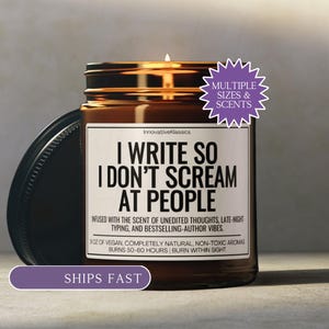 May include: A brown glass candle jar with a black lid, featuring a white label with the text "I WRITE SO I DON'T SCREAM AT PEOPLE." The candle is lit, and the label also includes the text "INFUSED WITH THE SCENT OF..." and "9 OZ OF VEGAN..."