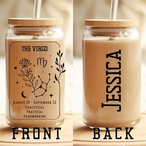 May include: A glass reusable cup with a bamboo lid and a straw. The front of the cup has a black and white design with the text "THE VIRGO" and the astrological symbol for Virgo. The text "AUGUST 23 - SEPTEMBER 22" is below the symbol. The text "ANALYTICAL, PRACTICAL, HARDWORKING" is below the dates. The back of the cup has the name "JESSICA" written vertically in black.