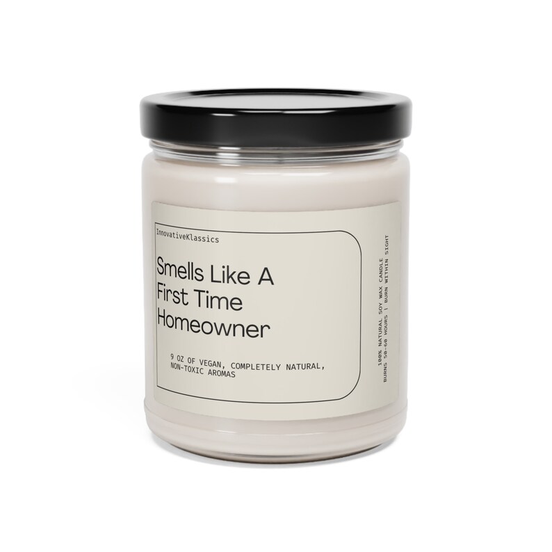 May include: A glass jar candle with a black lid. The label reads "Smells Like A First Time Homeowner" and "9 oz of Vegan, Completely Natural, Non-Toxic Aromas".