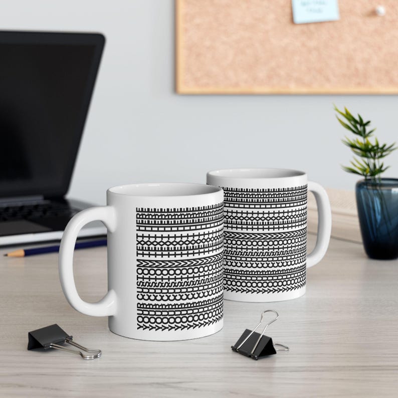 Pu&ograve; includere: Due tazze in ceramica bianca con motivi geometrici neri. I motivi includono trattini, cerchi e frecce. Le tazze hanno un manico standard e sono su una superficie chiara. Ogni tazza &egrave; alta circa 9,5 cm.