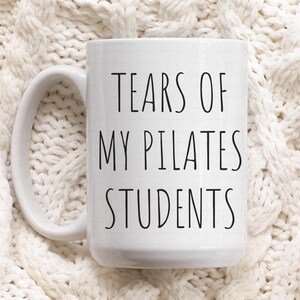 May include: White ceramic coffee mug with black text that reads "Tears of my Pilates students".
