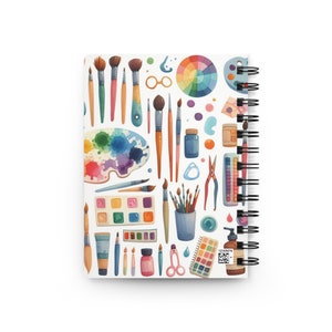 Puede incluir: Un cuaderno de espiral con un dise&ntilde;o de acuarela colorido que presenta pinceles, paletas de pintura y otros materiales de arte. La portada tiene un c&oacute;digo QR con el texto "12345678".