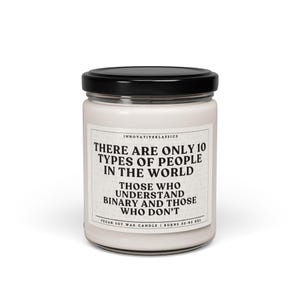 May include: A white soy wax candle with a black lid. The candle has a quote printed on the front: "There are only 10 types of people in the world. Those who understand binary and those who don't." The candle is vegan and burns for 50-60 hours.