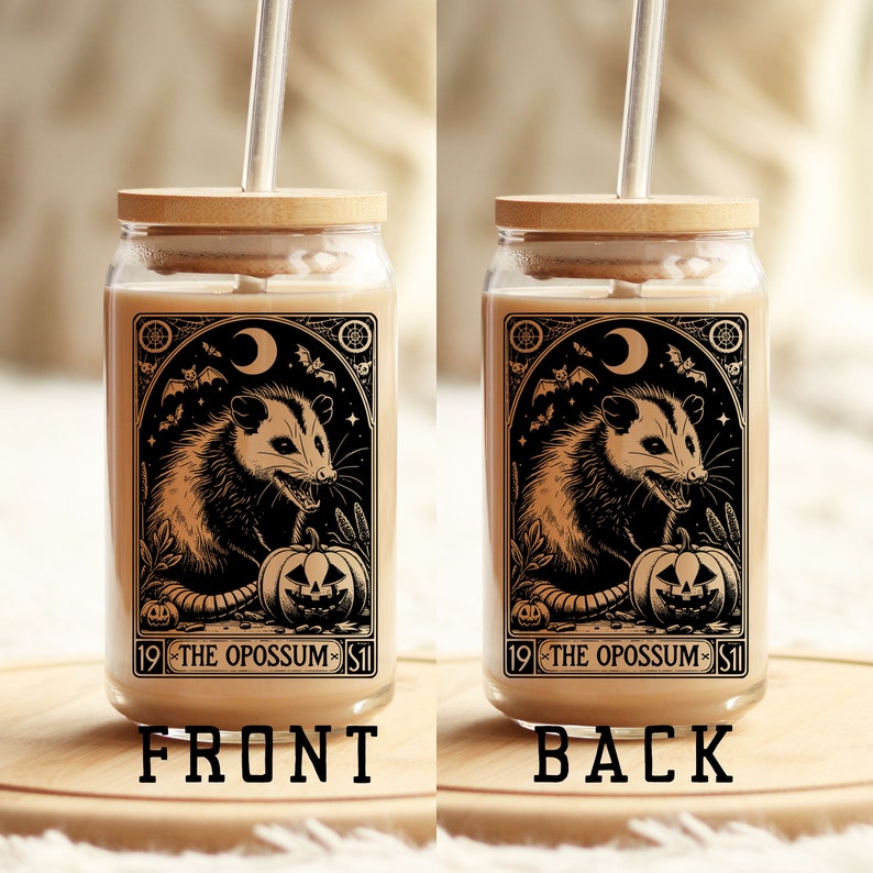May include: A glass jar with a wooden lid and a straw. The jar has a black and white illustration of an opossum with a pumpkin and bats. The text on the jar reads "19 - THE OPOSSUM - 51".