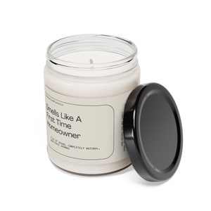 May include: A white candle in a clear glass jar with a black lid. The label reads "Smells Like A First Time Homeowner 8 oz of Vegan, Completely Natural, Non-Toxic Aromas".