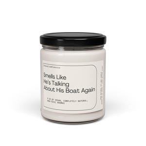 Op de afbeelding: Een witte kaars pot met een zwarte deksel. Het etiket luidt "Smells Like He's Talking About His Boat Again". De kaars is 9 oz vegan, volledig natuurlijk, niet-toxische aroma's.