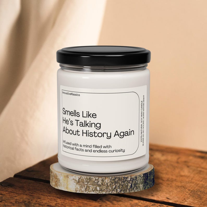 May include: A white candle with a black lid and a label that reads "Smells Like He's Talking About History Again" and "infused with a mind filled with historical facts and endless curiosity".