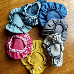 Puede incluir: Un juego de siete cubiertas de cuenco de tela en varios colores y patrones, incluyendo azul, gris, rojo, amarillo e impresiones florales. Las cubiertas están hechas de una tela suave y texturizada y tienen un borde elástico fruncido.