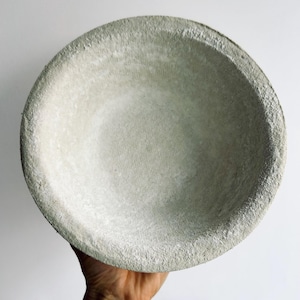 May include: A large, round, gray concrete bowl with a rough, textured surface.