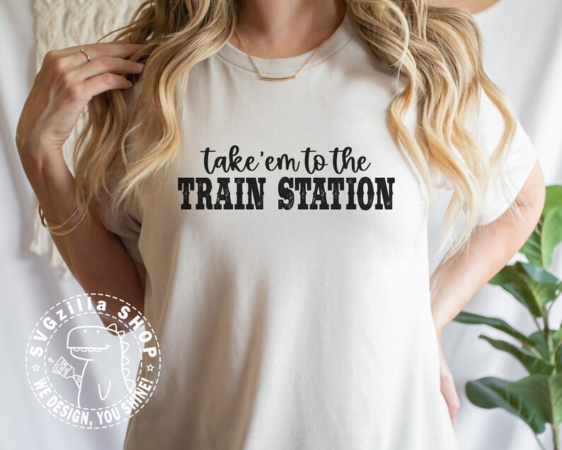 May include: White t-shirt with black text that reads "take 'em to the TRAIN STATION".