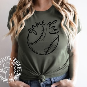 Op de afbeelding: Een groen T-shirt met de tekst "game day" en een zwart-witte baseball afbeelding.