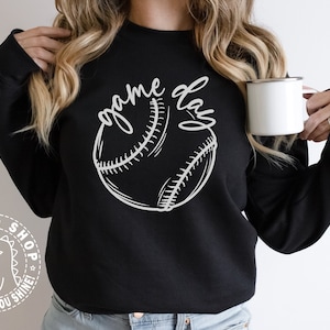 Op de afbeelding: Een zwart sweatshirt met een witte afbeelding van een honkbal en de tekst "game day".