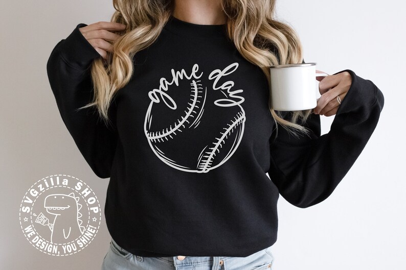Op de afbeelding: Een zwart sweatshirt met een witte afbeelding van een honkbal en de tekst "game day".