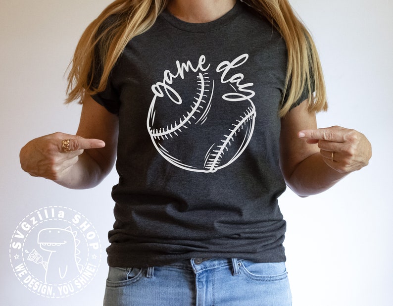 Op de afbeelding: Een donkergrijs T-shirt met een witte baseball en de tekst "game day" bedrukt op de voorkant.